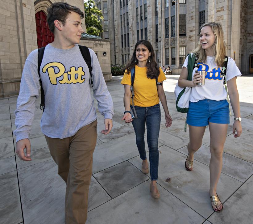 Three students walking across a college quad.