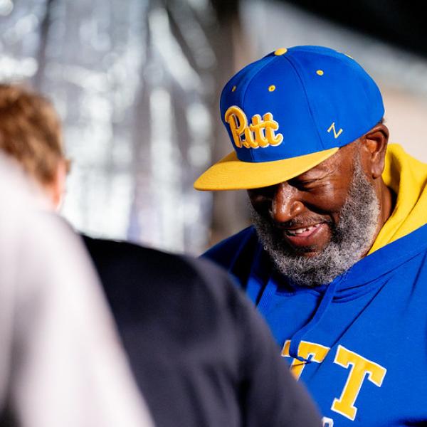 A man in a blue hat with a yellow brim smiling.