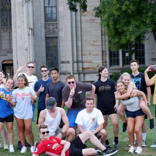 A group of students in athletic wear standing in front of the Cathedral of Learning.