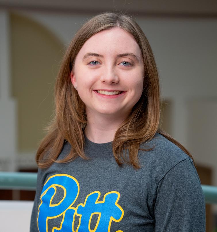 A woman with short brown hair smiling in a grey shirt.