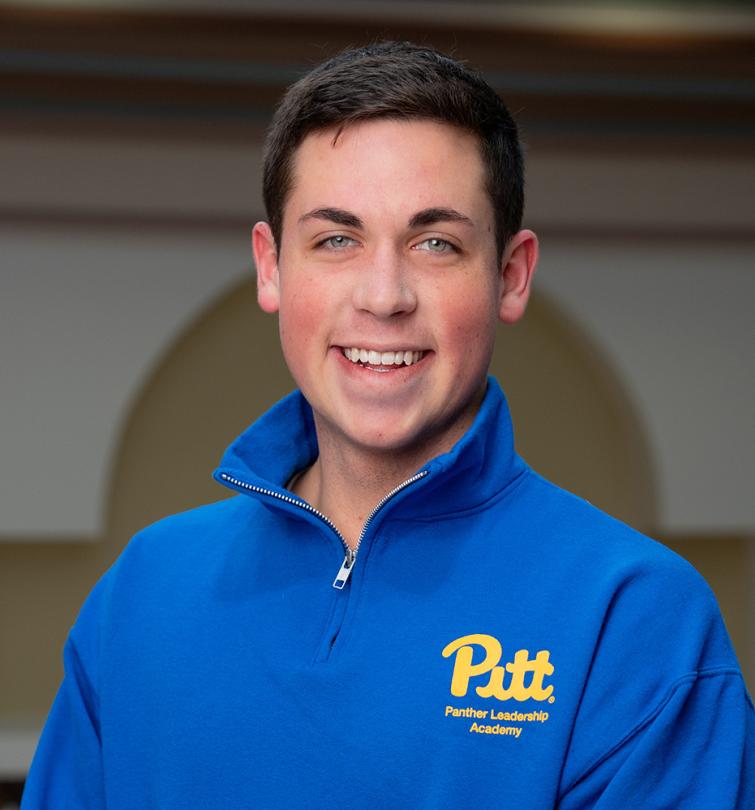 A man with short brown hair smiling in a blue quarter zip.