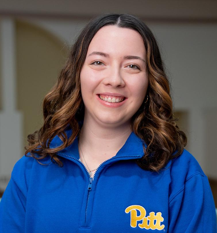 A woman with brown hair smiling in a blue quarter zip.