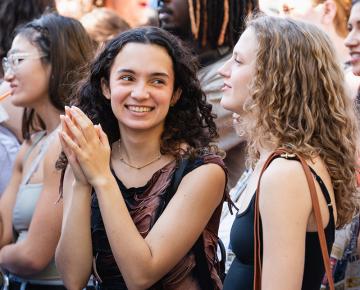 Two students with long curly hair standing in a crowd.
