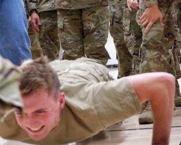 Student doing a push up while others watch.