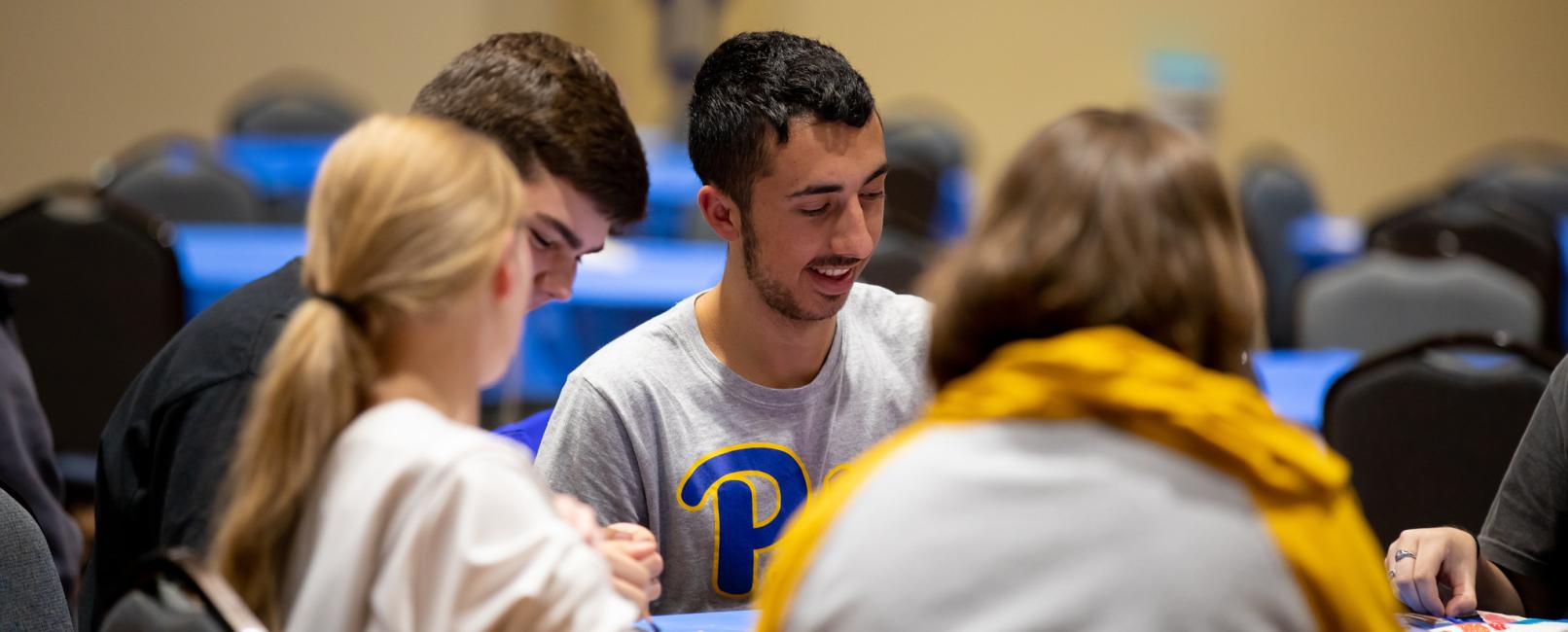 Four students sitting at a table making crafts.