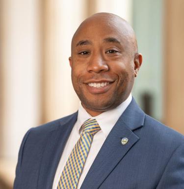 A man smiling in a blue suit.