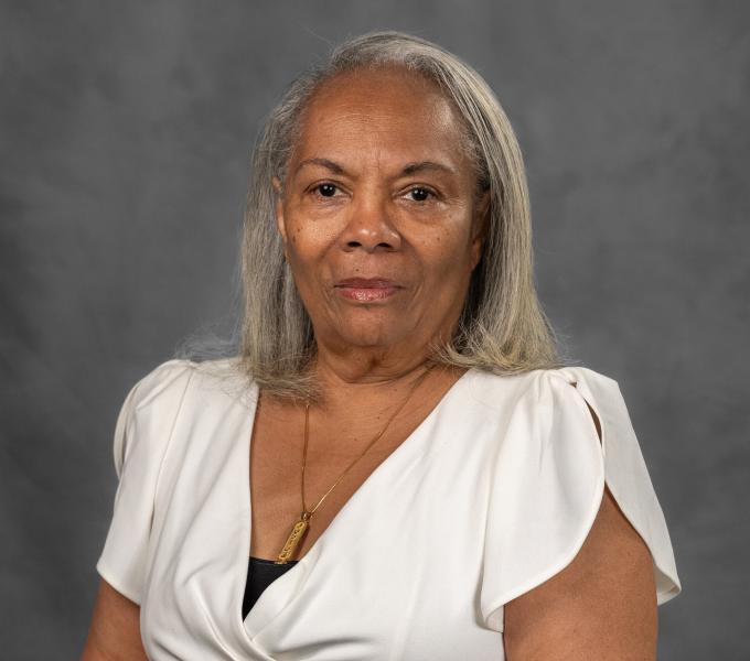 Headshot of a woman in a white blouse and gold pendant.