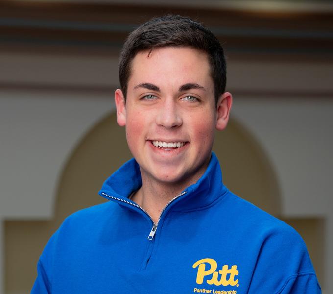 A man with short hair smiling with a blue quarter zip.