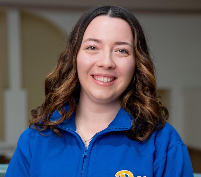 A woman with short brown hair smiling in a blue quarter zip.